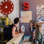 Backpackers consulting map at hostel reception desk for directions.