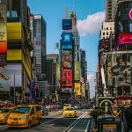 Dynamic street view of Times Square, NYC filled with billboards, taxis, and people.